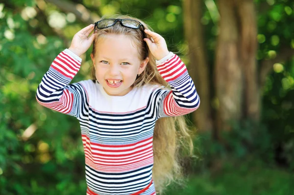 Süßes hübsches kleines Mädchen mit Brille im Freien in einem Park — Stockfoto