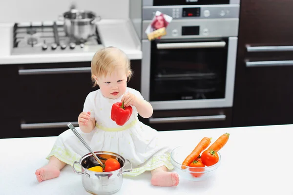 Little girl holding pepper on a kitchen — Stock Photo, Image