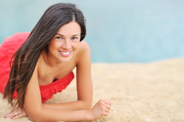 Vacker flicka ligger på en strand och ler — Stockfoto