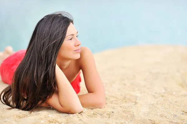 Krásná žena ležící na písku při pohledu na copyspace — Stock fotografie