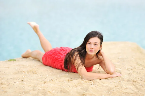 Vacker kvinna liggande på en sand nära en strand — Stockfoto