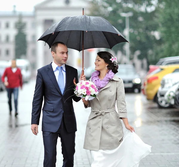 Wedding couple waking by the rain in an old town — Stock Photo, Image