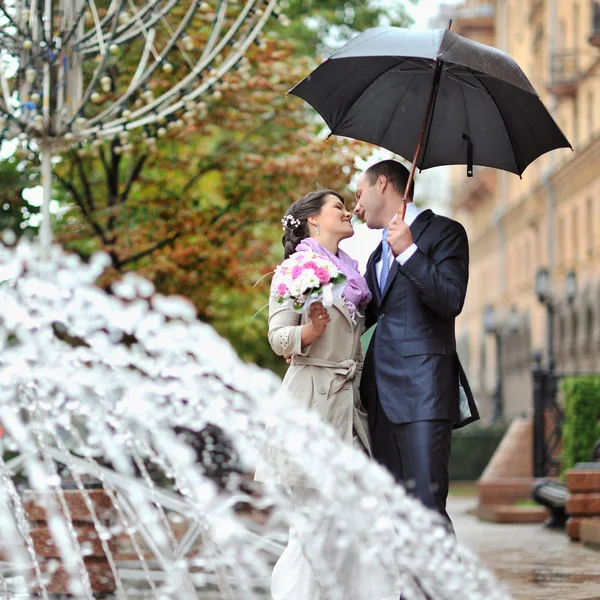Beijar o casal de casamento em um dia de casamento chuvoso — Fotografia de Stock