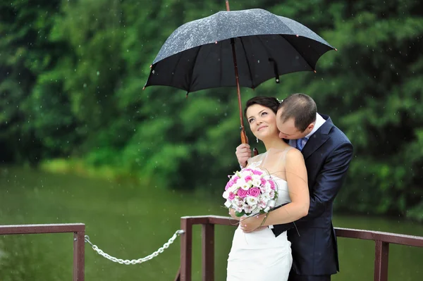 在一个下雨天接吻的浪漫婚礼夫妇 — 图库照片