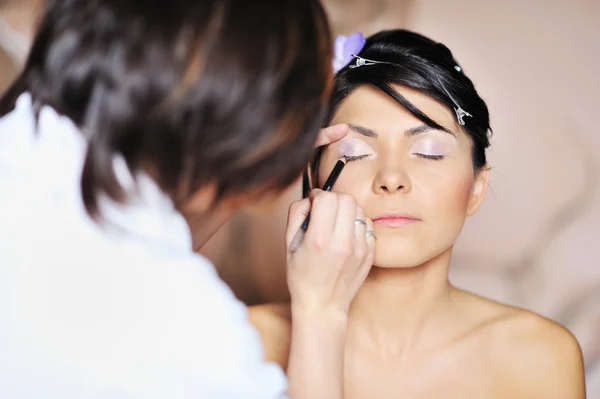 Jeune belle mariée appliquant maquillage de mariage par maquilleur — Photo