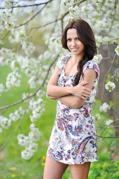 Mulher jovem sorridente bonita em um parque de pé com as mãos dobrar — Fotografia de Stock