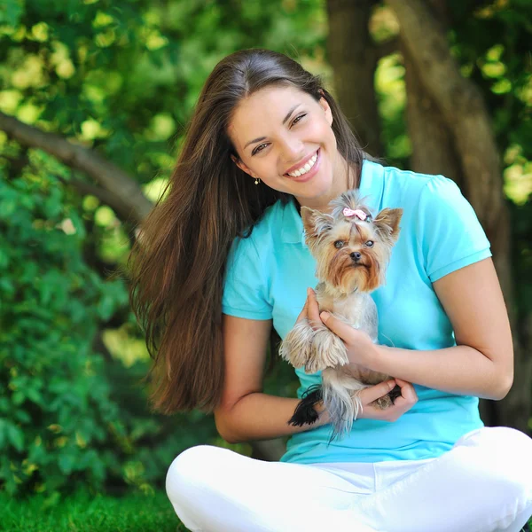 Woman playing with her little puppy in a green park — Stock Photo, Image