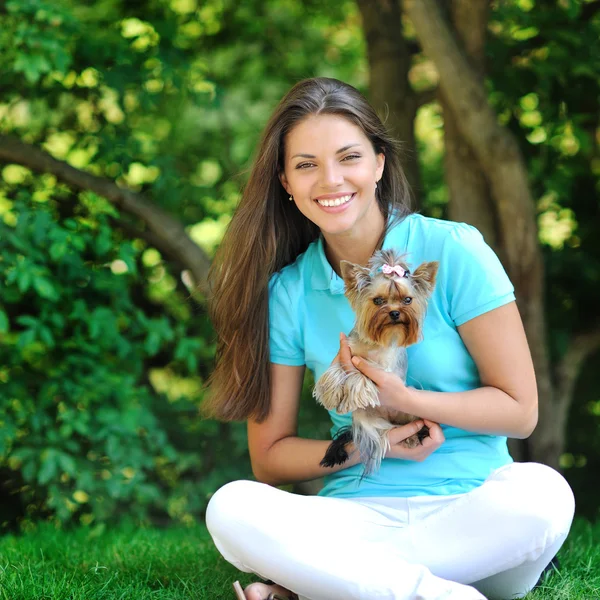 Güzel genç kadın ile yeşil s karşı küçük köpek gülümsüyor — Stok fotoğraf