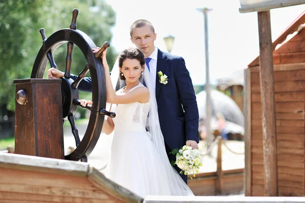 Bruden och brudgummen nära fartyget ratt — Stockfoto