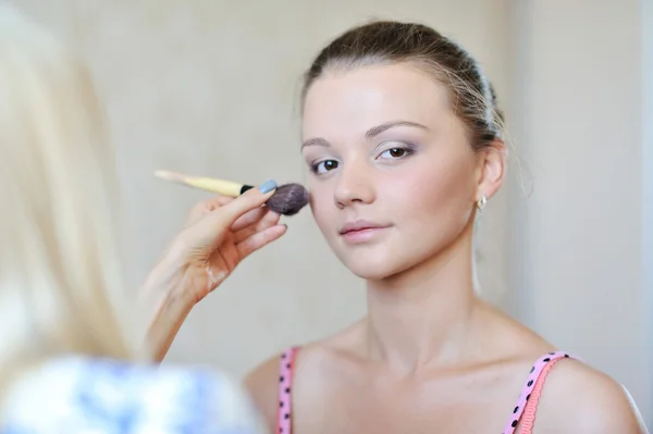 Joven hermosa mujer aplicando maquillaje por maquillador — Foto de Stock