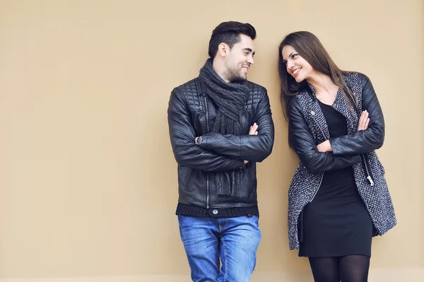 Jovem feliz casal alegre de pé perto de uma parede e olhando para — Fotografia de Stock