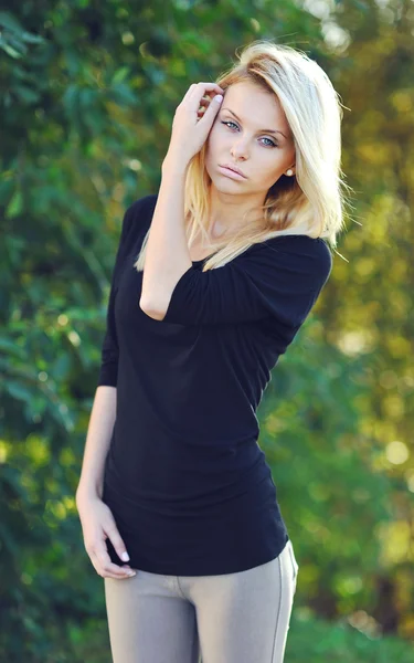 Fashion portrait of a beautiful young woman in a summer park — Stock Photo, Image