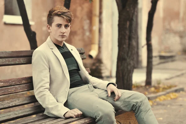 Young handsome man sitting on a bench — Stock Photo, Image