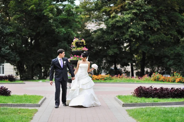 Bride and groom walking in a green park — Stock Photo, Image