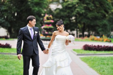 Gelin ve damat yeşil bir parkta yürüyüş