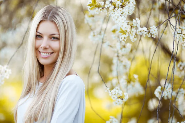 Outdoor portrait of a beautiful blonde woman in blue dress among — Stock Photo, Image