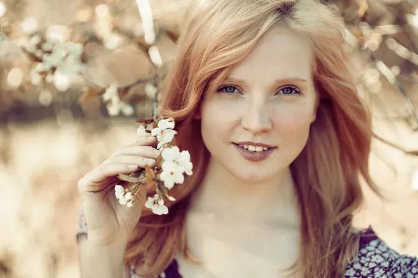 Menina bonita em uma árvore florescente — Fotografia de Stock