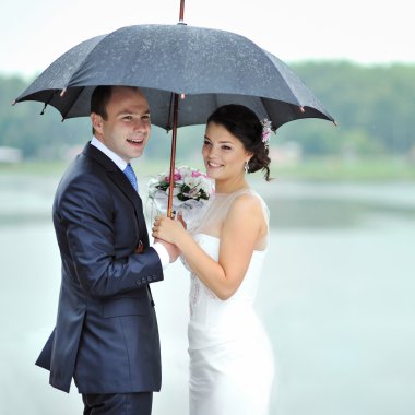 mutlu gelin ve damat yağmurdan gizleme yağmurlu düğün günü içinde