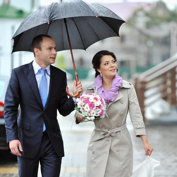 Sposa e sposo che camminano insieme in un giorno di pioggia — Foto Stock