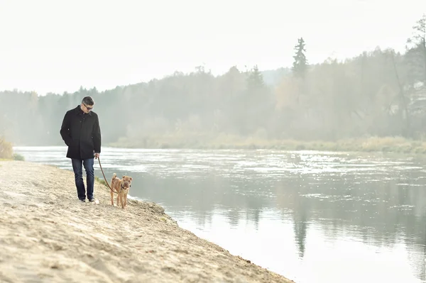 Uomo che cammina con cane vicino al fiume — Foto Stock