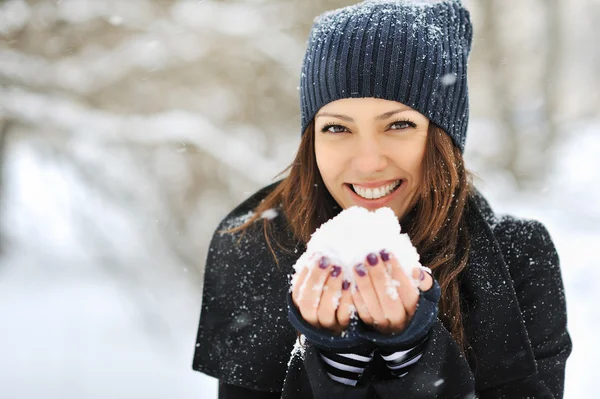 Vacker kvinna leker med snö i park — Stockfoto