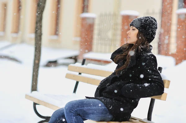 Jeune femme assise sur le banc dans le parc et regardant loin — Photo