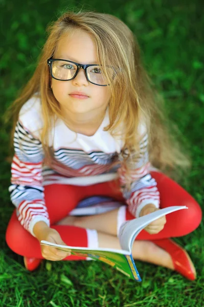 Niña enojada y cansada con un libro en un parque — Foto de Stock