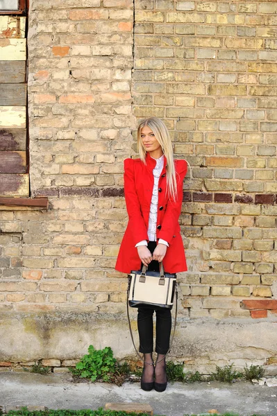 Portrait of slim girl standing near a wall in red dress with han — Stock Photo, Image