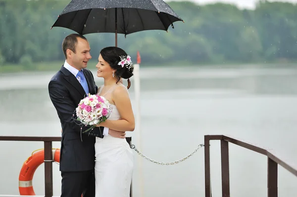 Happy young bride and groom in a rainy day — Stock Photo, Image