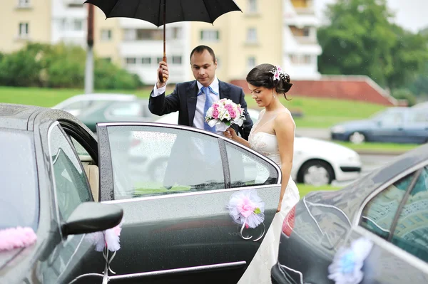 Jonge bruidspaar krijgen in een auto — Stockfoto