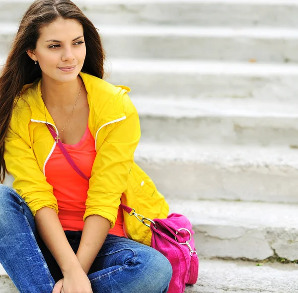 Stylish beautiful teen girl sitting on a stairs in colorful clot — Stock Photo, Image