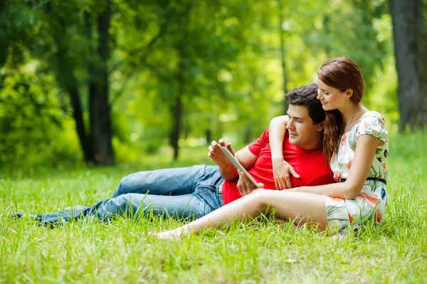 Hermosa pareja romántica con PC tableta en el parque verde de verano — Foto de Stock