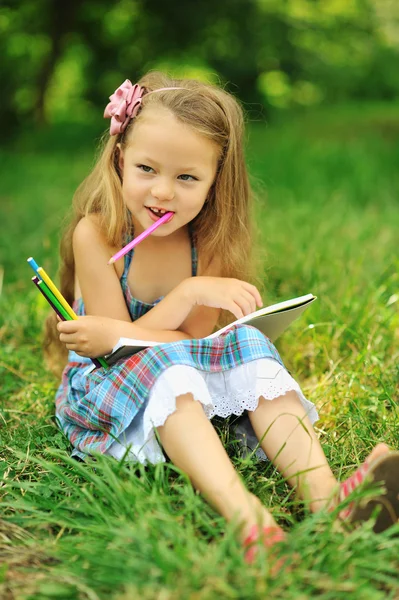 Menina bonito com lápis e nota em um parque — Fotografia de Stock