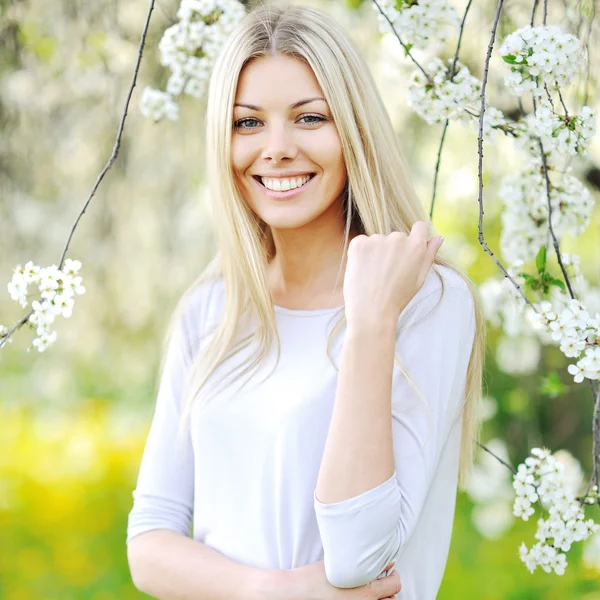 Mooi meisje in de tuin onder de bloeiende bomen — Stockfoto