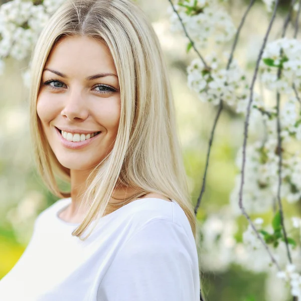 Retrato de una hermosa chica en el árbol de flores de fondo — Foto de Stock