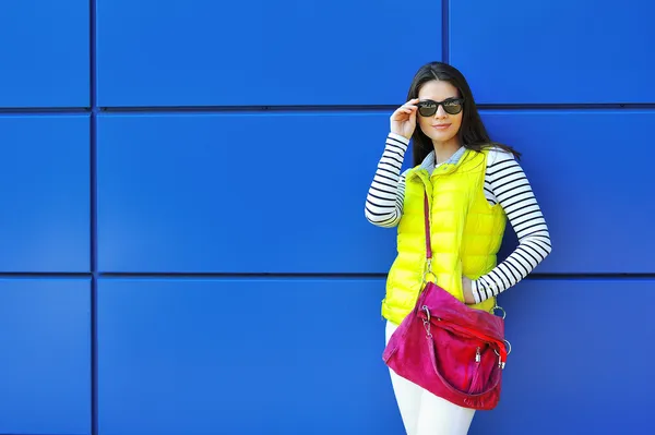 Stylish beautiful girl standing near blue wall — Stock Photo, Image