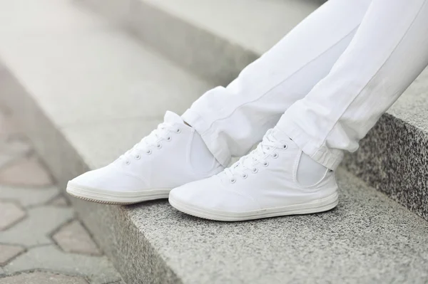 Sneakers bianche sulle gambe della ragazza - primo piano — Foto Stock