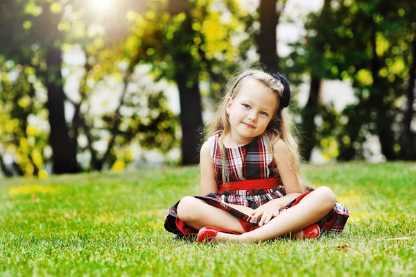 Vackra lilla flicka stående i en sommar grön park — Stockfoto