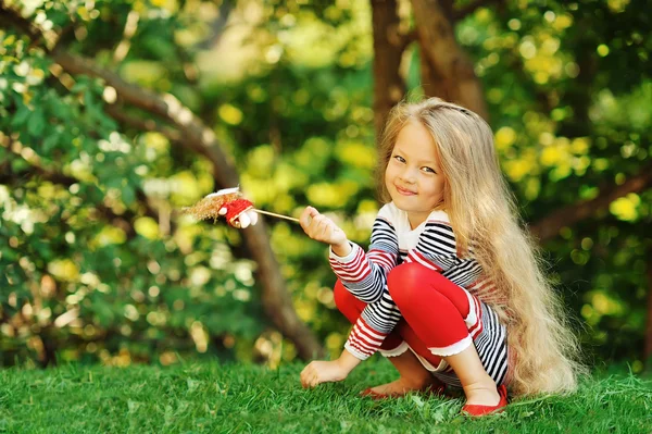 Foto av söt liten flicka sitter på grönt gräs — Stockfoto