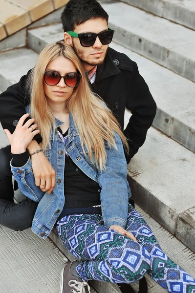 Pareja joven de moda sentada en las escaleras y abrazándose unos a otros — Foto de Stock