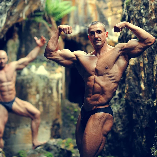 Two bodybuilders posing in a cave — Stock Photo, Image