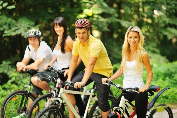 Group of attractive happy people on bicycles in the countryside — Stock Photo, Image