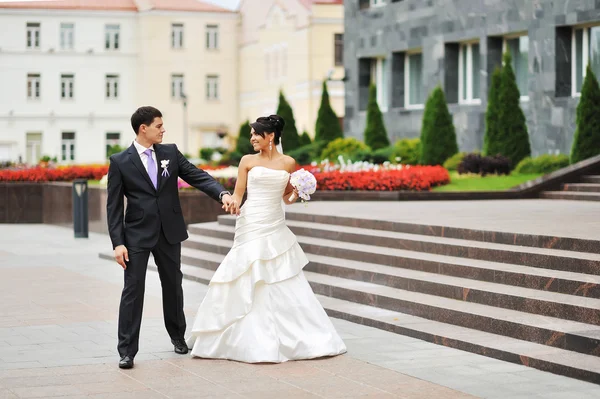 Happy bride and groom walking in an old town — Stock Photo, Image