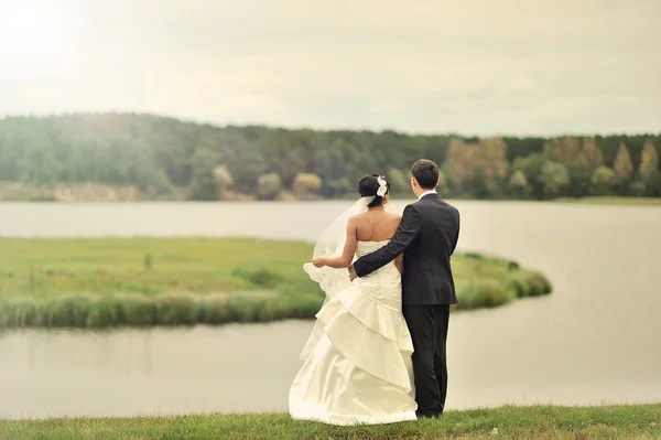 湖の近くに立っている結婚式のカップル — ストック写真