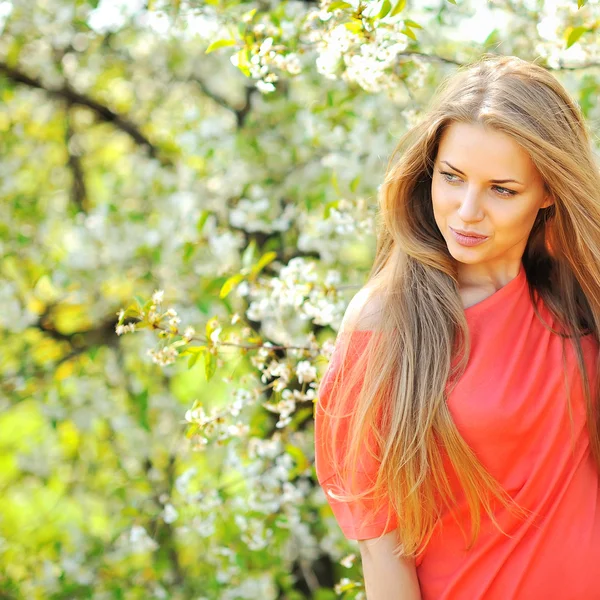 Beautiful young blonde woman standing near blooming tree - copys — Stock Photo, Image