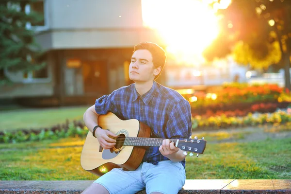 Jovem tocando guitarra acústica no parque — Fotografia de Stock