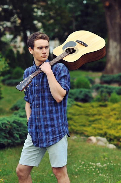 Young stylish hipster man with guitar in the park — Stock Photo, Image