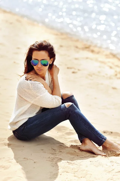 Sexig brunett kvinna sitter på en strand — Stockfoto