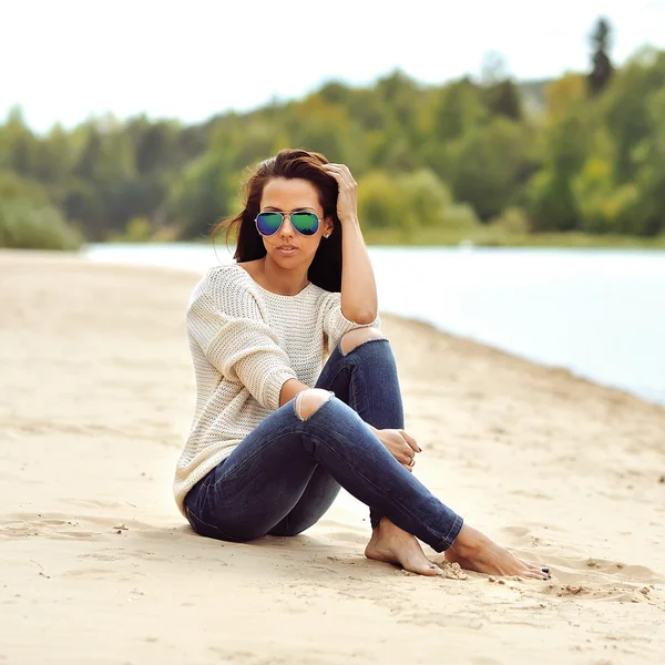 Young beautiful woman in sunglasses sitting on a beach — Stock Photo, Image