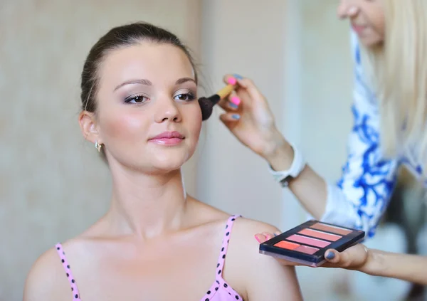 Joven hermosa mujer aplicando maquillaje por maquillador — Foto de Stock